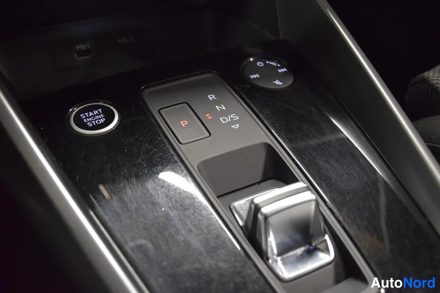 Yksityiskohta: Auton keskikonsolin vaihteenvalitsin ja käynnistyspainike: START ENGINE STOP -painike ja R-N-D/S-vaihdenäppäimet.