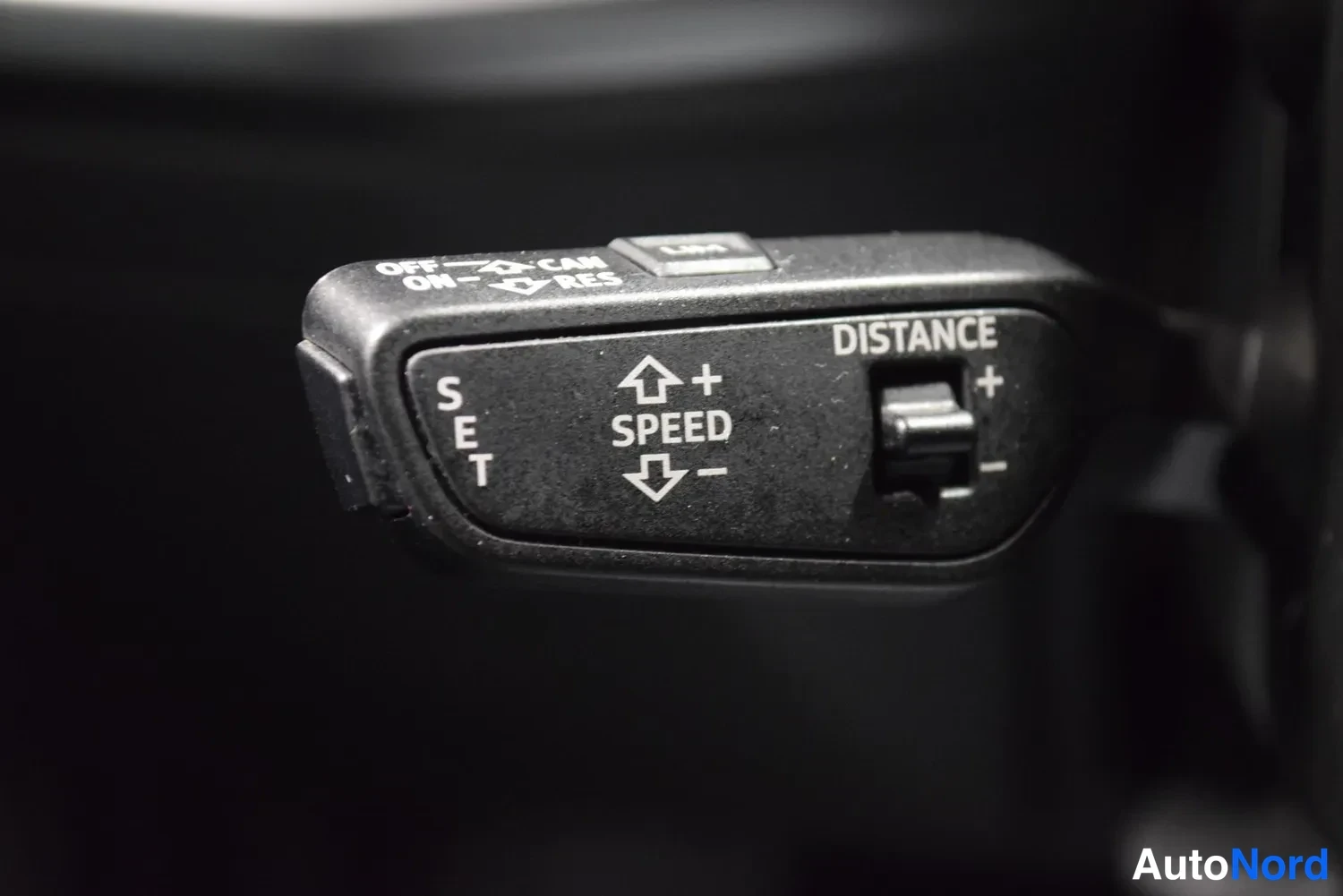Yksityiskohta: Vilkkuvalitsimen arteri: cruisesäädin, jossa tekstit SET, SPEED, RES, OFF ja DISTANCE-säädin.
