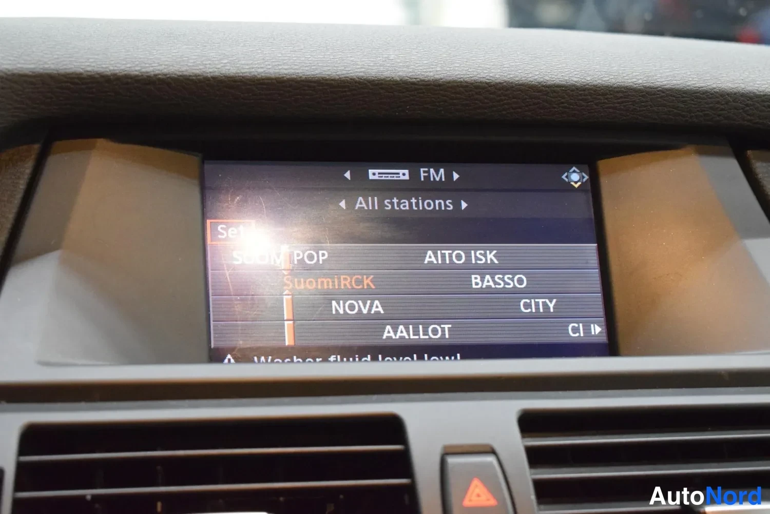 Muu: Radio FM -valikko All stations, kanavina SuomiRCK, AALLOT, AITO ISK, BASSO, CITY, NOVA. Näytön alaosassa varoitus Washer fluid level low.