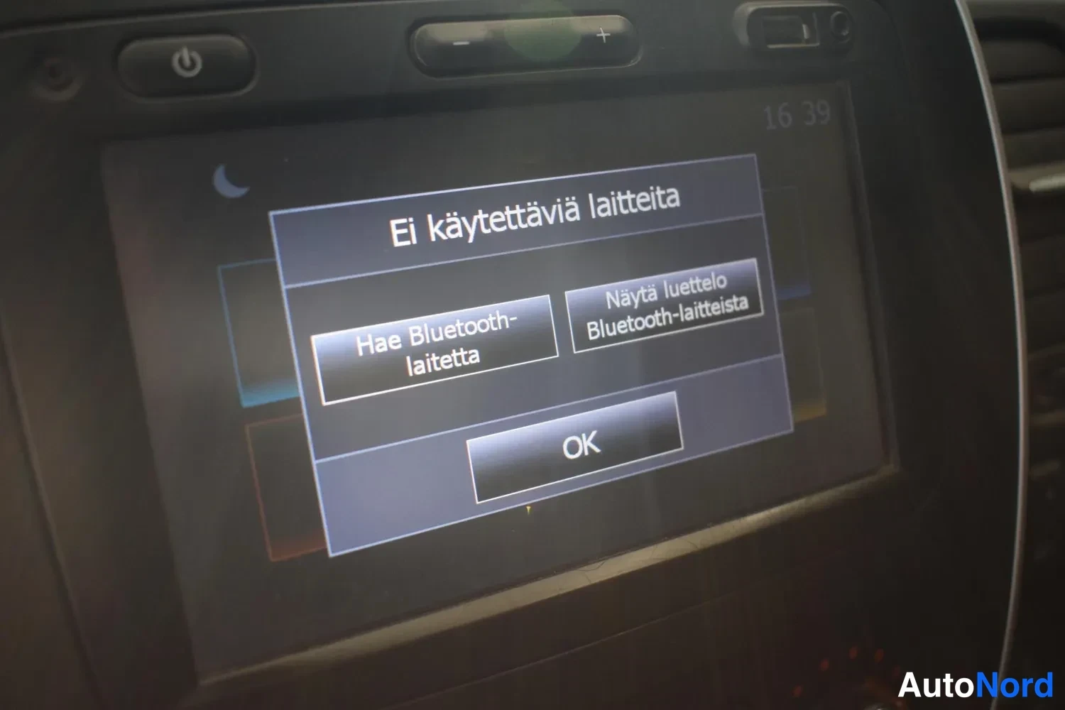 Yksityiskohta: Auton kosketusnäytön Bluetooth-ruutu, jossa teksti 'Ei käytettäviä laitteita' ja vaihtoehdot 'Hae Bluetooth-laitetta' ja 'Näytä luettelo Bluetooth-laitteista' s