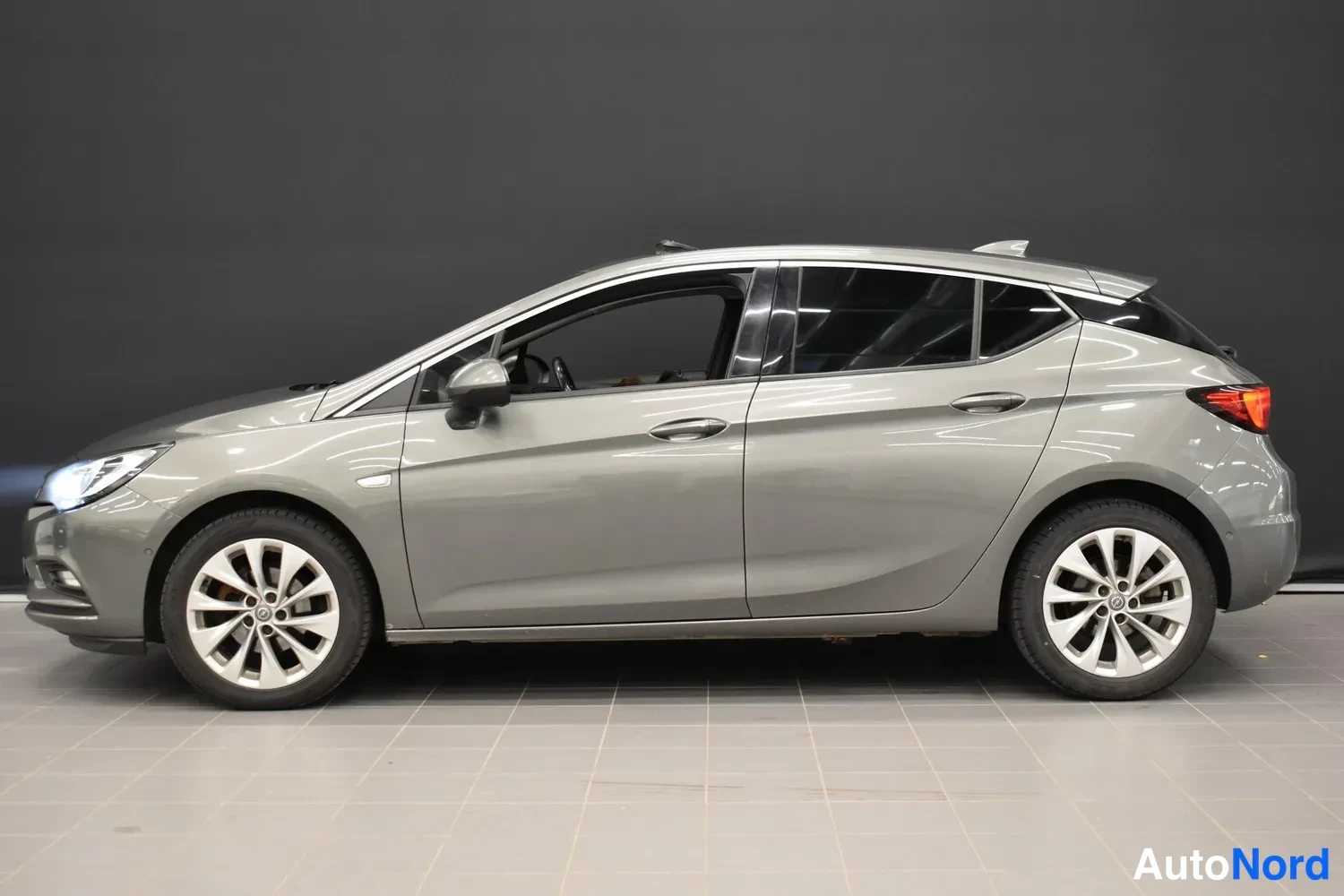 Sivulta: Opel Astra -henkilöauto harmaana kuvattuna sivusuunnasta, ovet ja takavalot näkyvät.