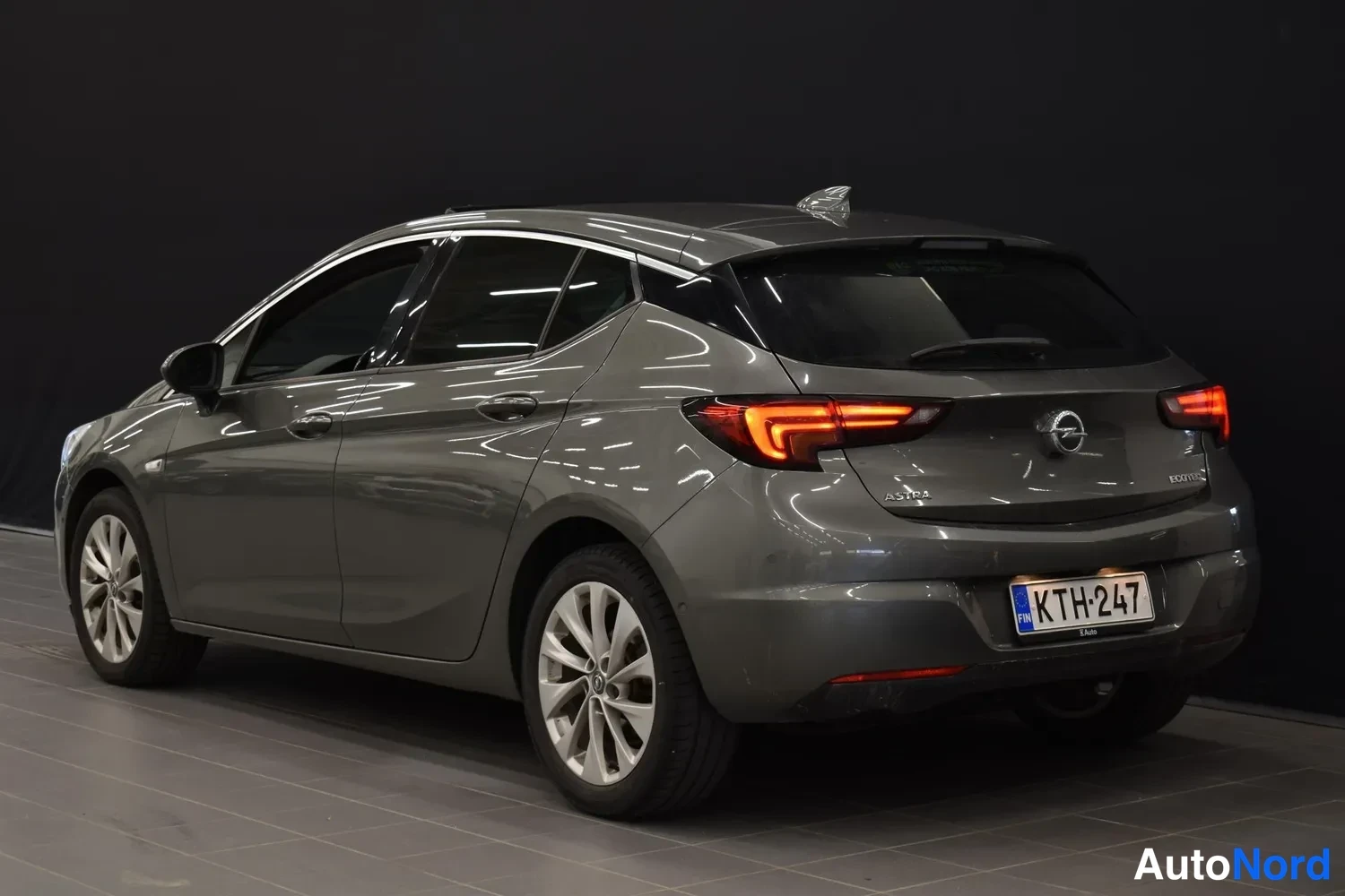 Takaviisto: Opel Astra -henkilöauto harmaana kuvattuna takakulmasta, takavalot ja rekisterikilpi näkyvät.