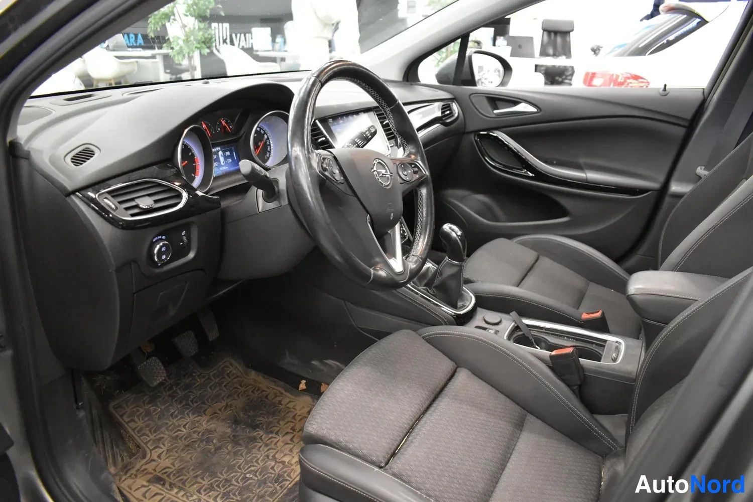 Sivulta: Ohjaamo kuljettajan puolelta: Opel-merkkinen ratto, mittaristo ja vaihtaja.