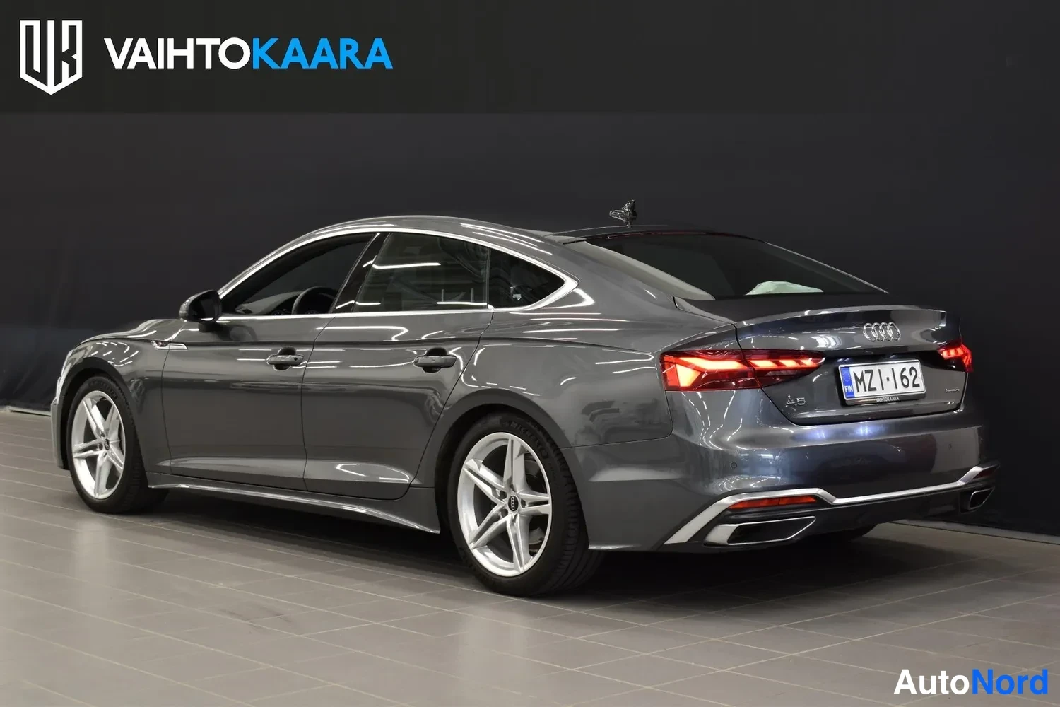 Takaviisto: Audi A5 Sportback takaosoalta vasemmalta kuvattuna, tummanharmaa kori, LED-takavalot ja hopeavanteet.
