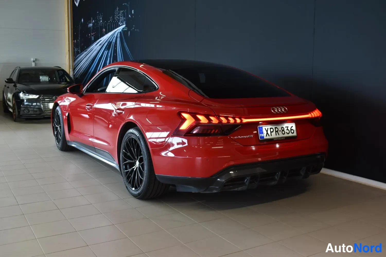 Takaviisto: Punaisen Audi e-tron GT:n takakulma sisätiloissa, valaistu takavalot ja rekisterikilpi.