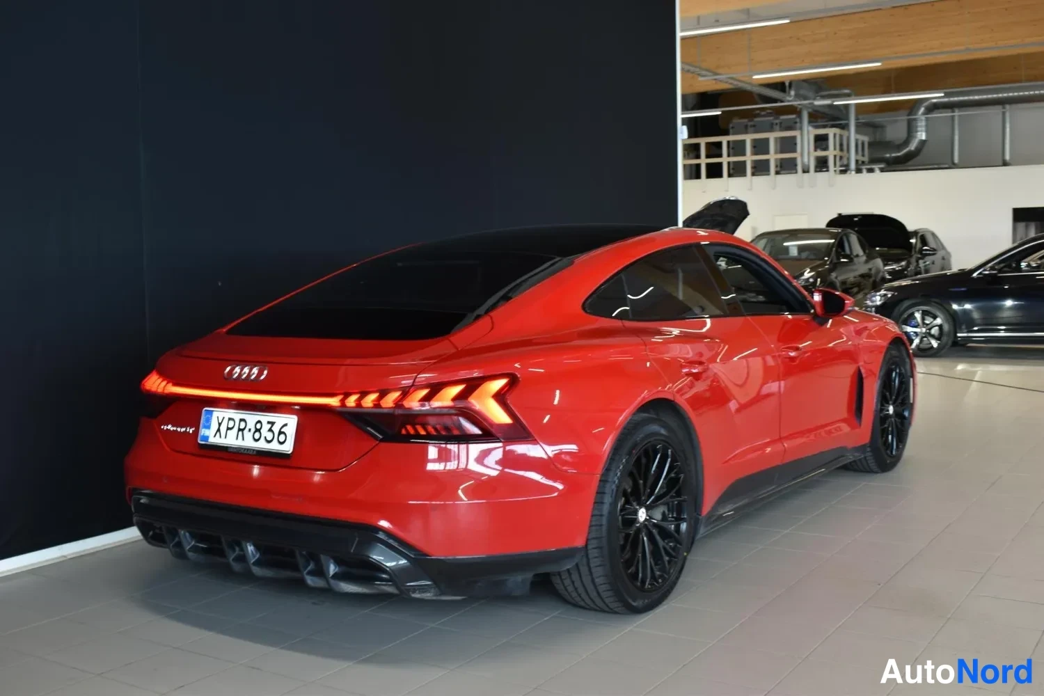 Takaviisto: Punainen Audi e-tron GT takakulmasta sisätiloissa, rekisterikilpi, mustat vanteet.
