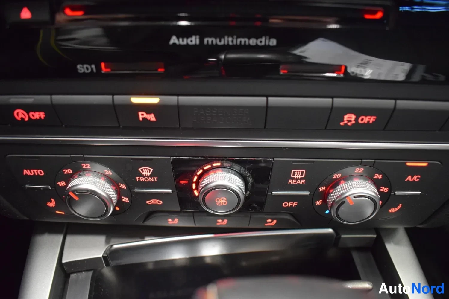 Muu: Sisäkuva: keskikonsolin lämmitys- ja ilmastointipaneeli (Audi multimedia), jossa AUTO, A/C, FRONT ja REAR -näppäimet sekä lämpötilanupit, p_ot 0 ja 22 lukemilla