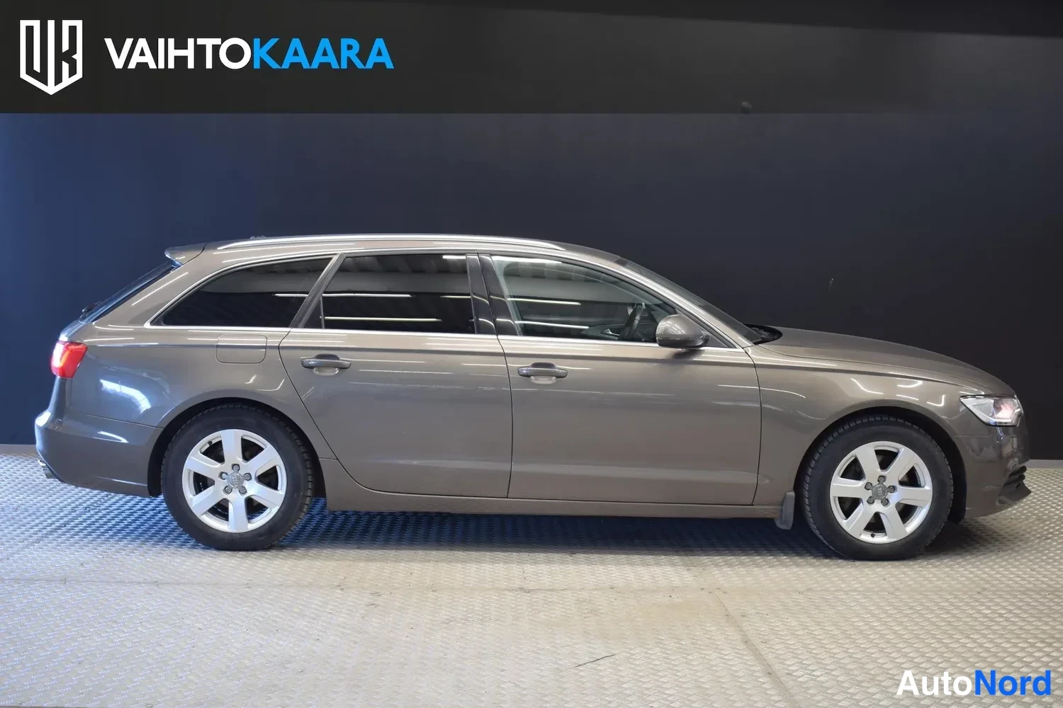 Etuviisto, nokka oikealle: Audi A6 Avant -farmari sivulta kuvattuna, harmaanruskea kori ja hopeiset peltivanteet.