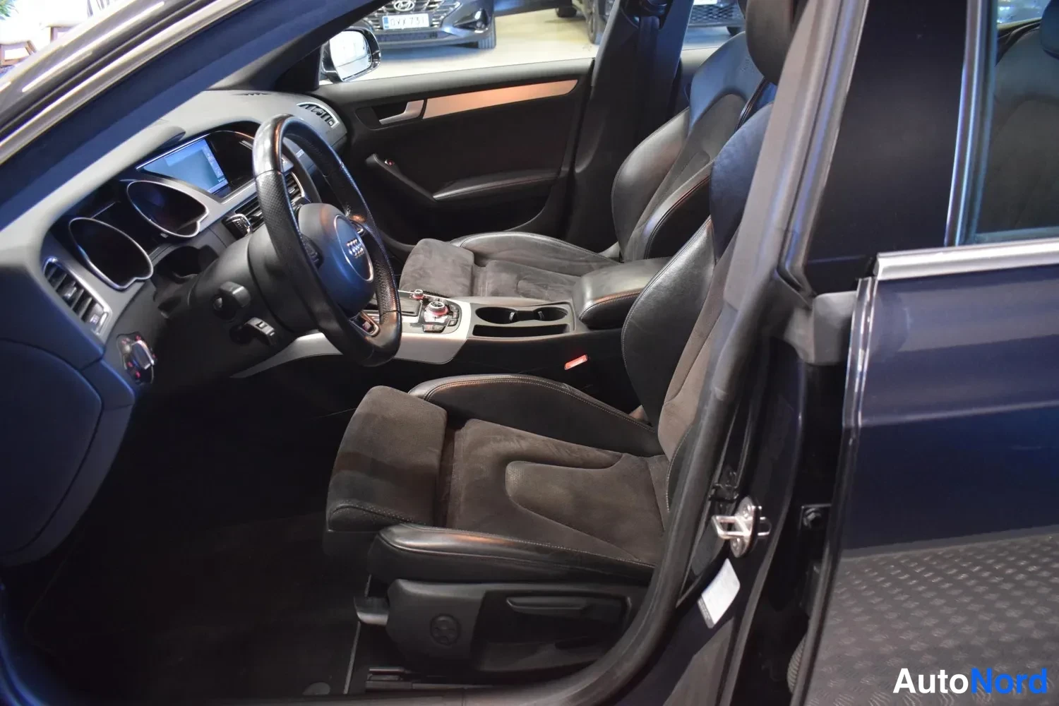 Muu: Audi A5 Sportback sisätilan kuva kuljettajan oven avattua, tummat etuistuimet ja kojelauta näkyvät
