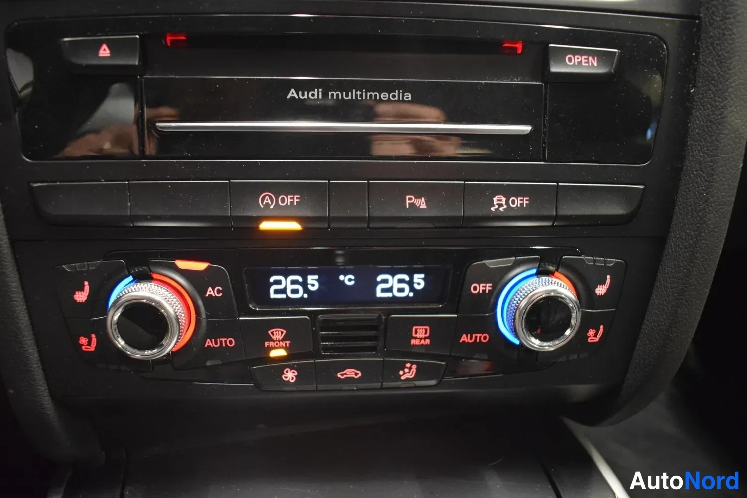 Edestä: Keskikonsolin paneeli: Audi multimedia -yksikkö, ESP OFF- ja parkkitutkan painikkeet sekä ilmastointipaneeli näytöllä 26,5 °C.