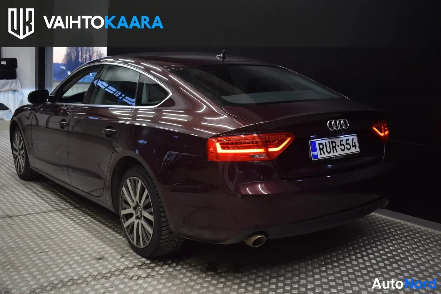 Takaviisto: Tummanpunainen Audi A5 Sportback takaa vasemmalta kuvattuna, rekisterikilpi.