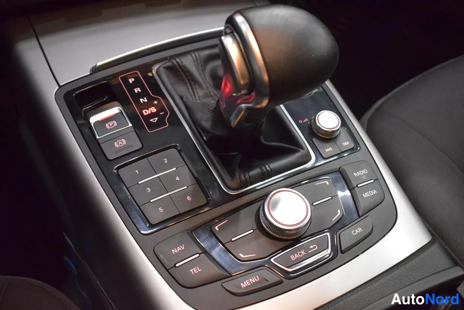 Yksityiskohta: Keskiökonsolin automaattivaihteiston valitsin ja MMI-ohjainnäppäimet, NAV-, TEL-, RADIO-, MEDIA- ja CAR-painikkeet.