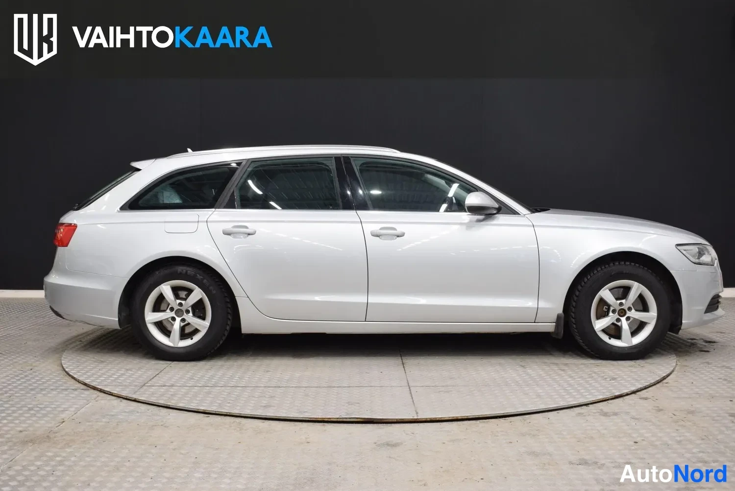 Etuviisto, nokka oikealle: Audi A6 Avant sivusta oikeaan etukulmaan, hopeinen farmarikorinen auto studio­taustaa vasten.