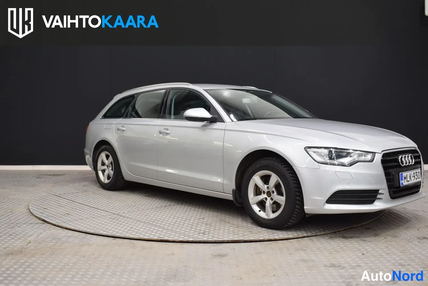 Etuviisto, nokka oikealle: Audi A6 Avant etu­oikealta kulmalta, hopeinen auto, etusäleikkö ja Audi-merkki näkyvissä, rekisterikilpi.