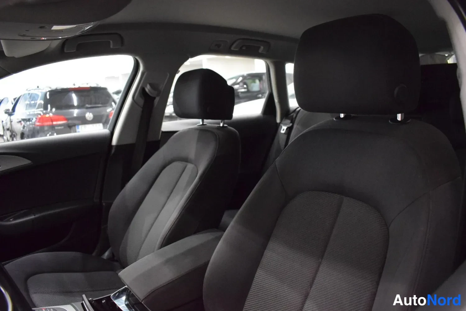 Muu: Audi A6:n tummanharmaat kankaanistuimet sisältä kuvattuna, etuistuimet ja takaistuimen niskatule One huoneistossa.