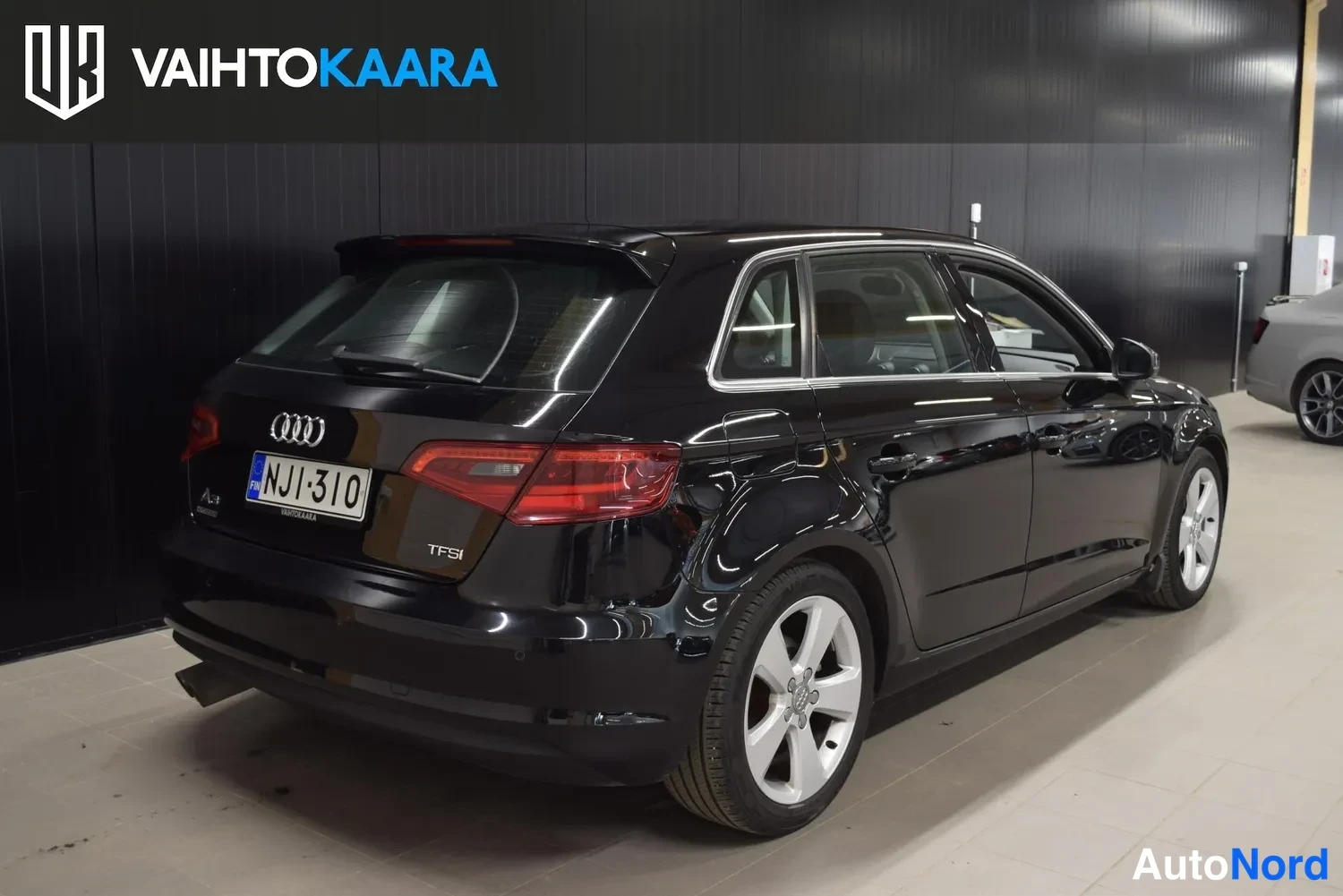 Takaviisto: Musta Audi A3 Sportback takakulmasta kuvattuna, TFSI-merkintä, takavalot ja rekisterikilpi näkyvät.