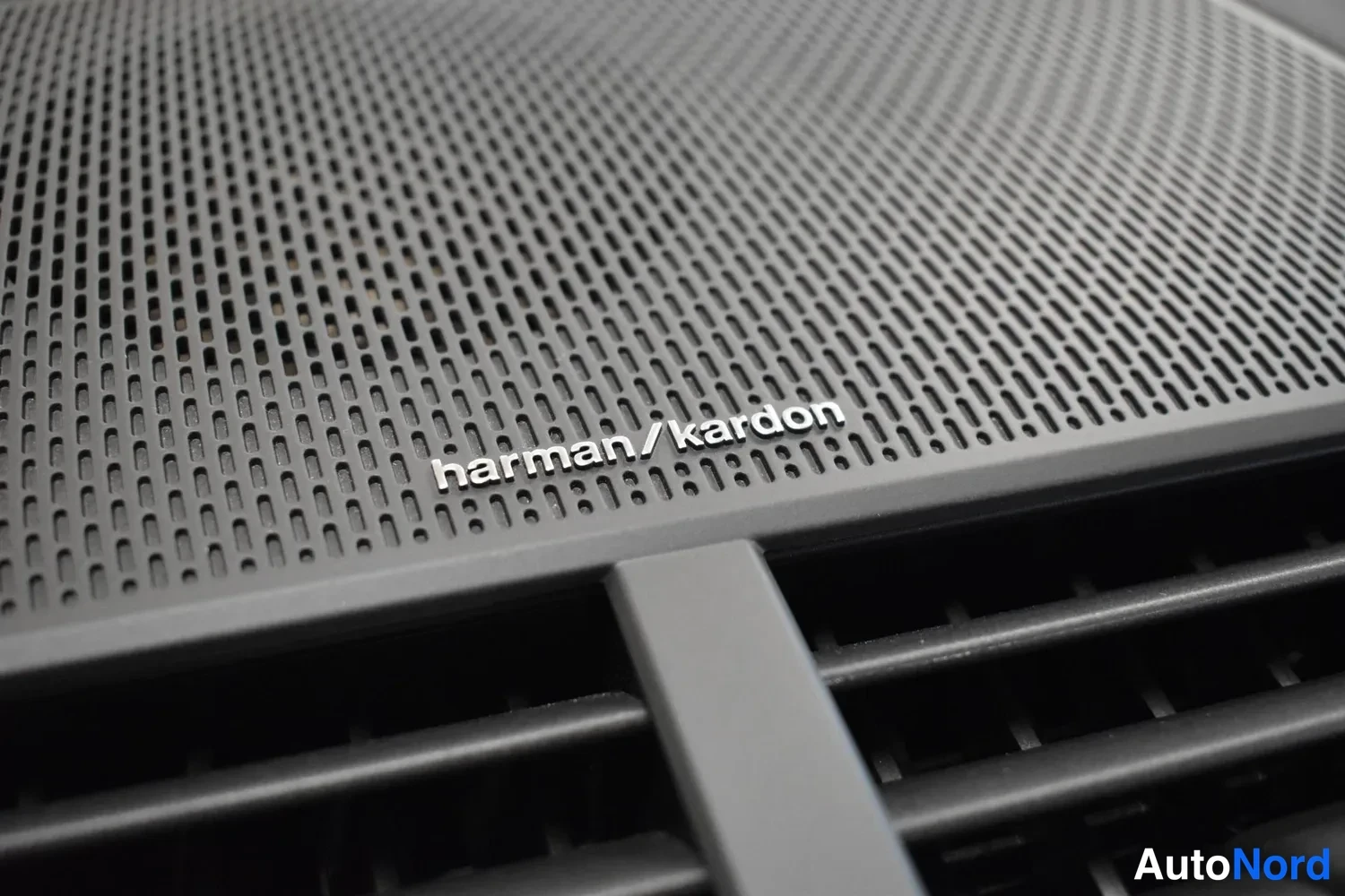 Yksityiskohta: Harman Kardon -kaiuttimen harmaa verkko­ritilä, jossa lukee 'harman/kardon'.