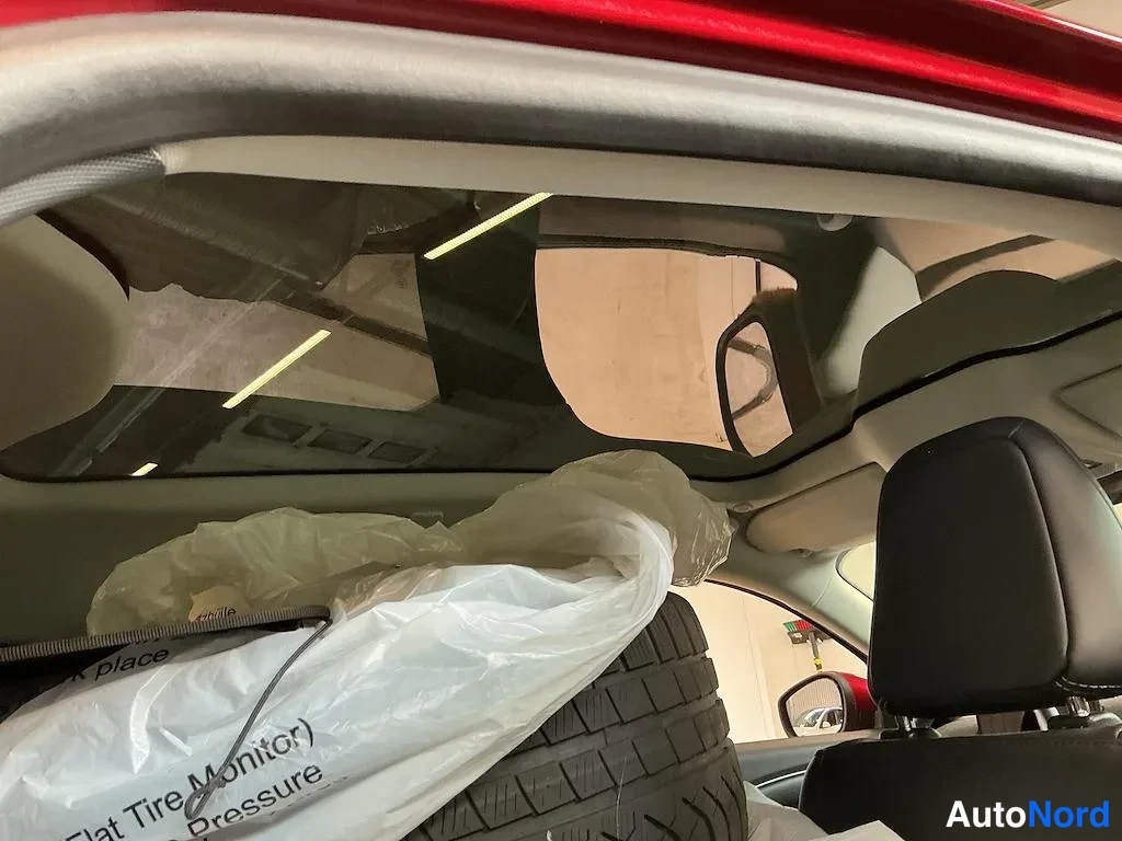 Muu: Takapenkin taakse varastoitunut keskitapitön vararengas ja maahantulopaketti (Flat Tire Monitor) -pussi; katossa lasikatto.