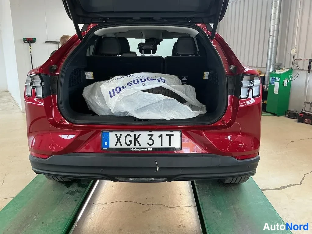 Takaa: Punaisen auton takaosa avoimella tavaratilalla, ruotsalainen rekisterikilpi XGK 31T.