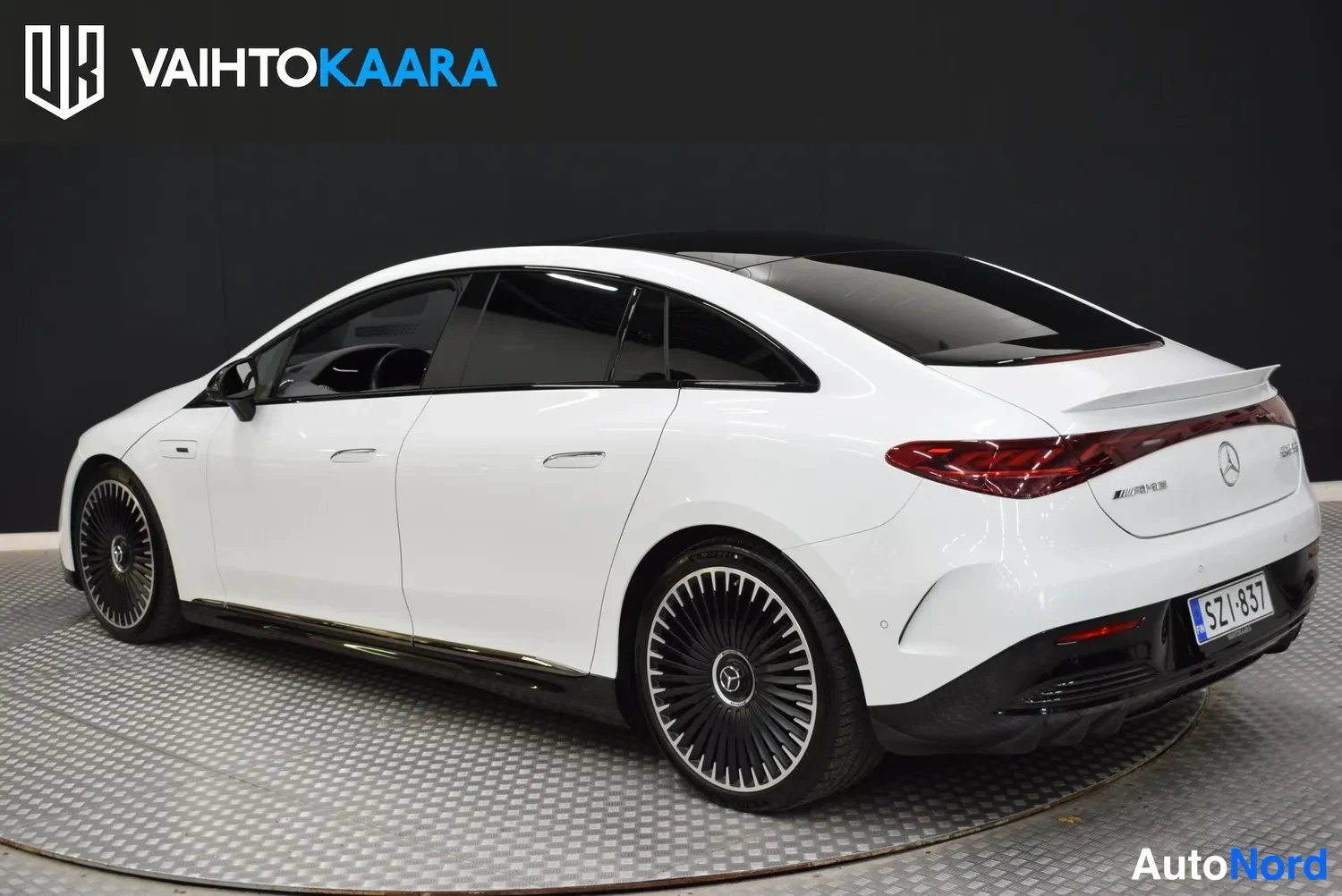 Takaviisto: Mercedes-Benz EQE 53 4MATIC 2023 takaa vasemmasta takakulmasta kuvattuna, valkoinen kori, punaiset takavalot ja tummat vanteet.