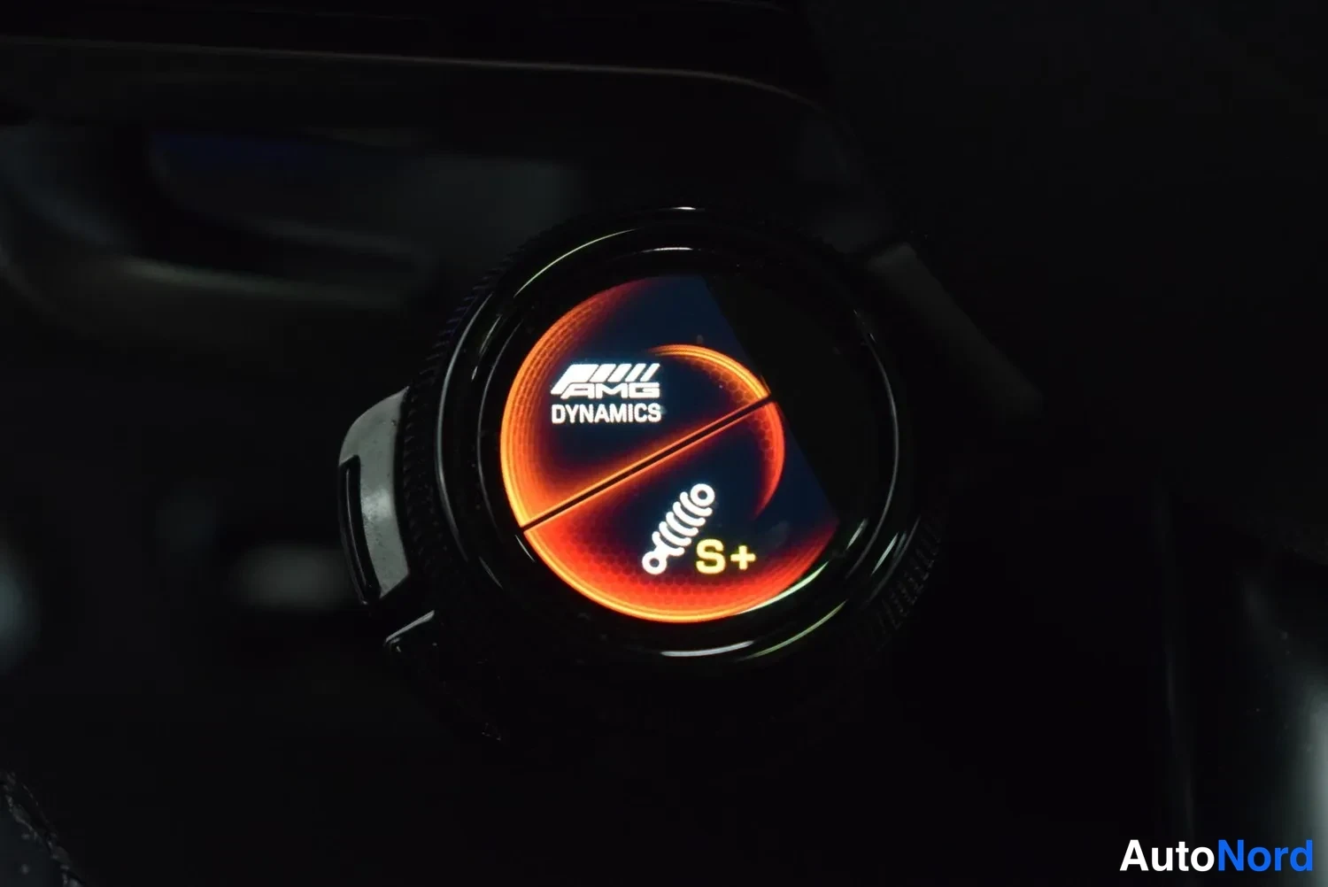 Muu: Sisätiloissa sijaitseva pyöreä valitsin, jonka näytöllä lukee AMG DYNAMICS ja alla oranssilla S+.