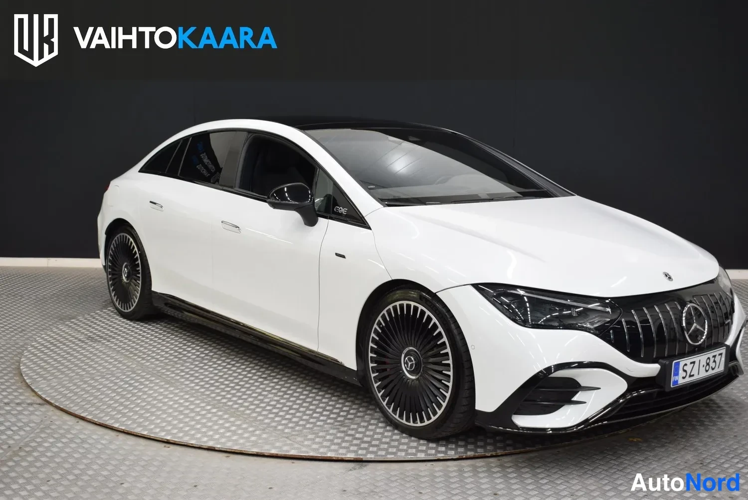 Etuviisto, nokka oikealle: Valkoinen Mercedes-Benz EQE etuviistosta oikealta, keula oikeassa kulmassa.