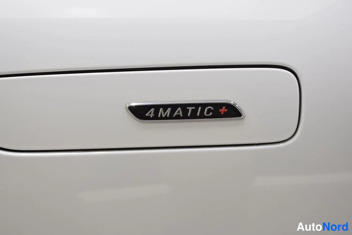Yksityiskohta: Lähikuva 4MATIC+ -merkinnästä valkoisessa koripaneelissa.