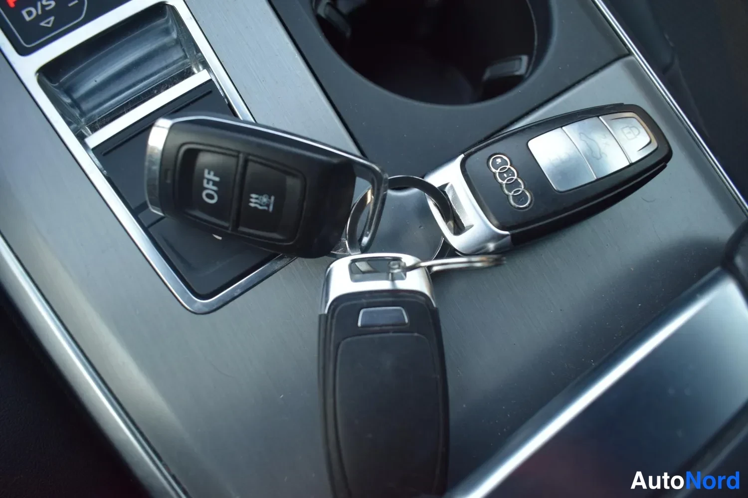 Muu: Kolme Audi-avainketjua keskitunnelin metallikoristeiden päällä; yhdessä avaimessa OFF-kytkin, toisessa Audi-logo.