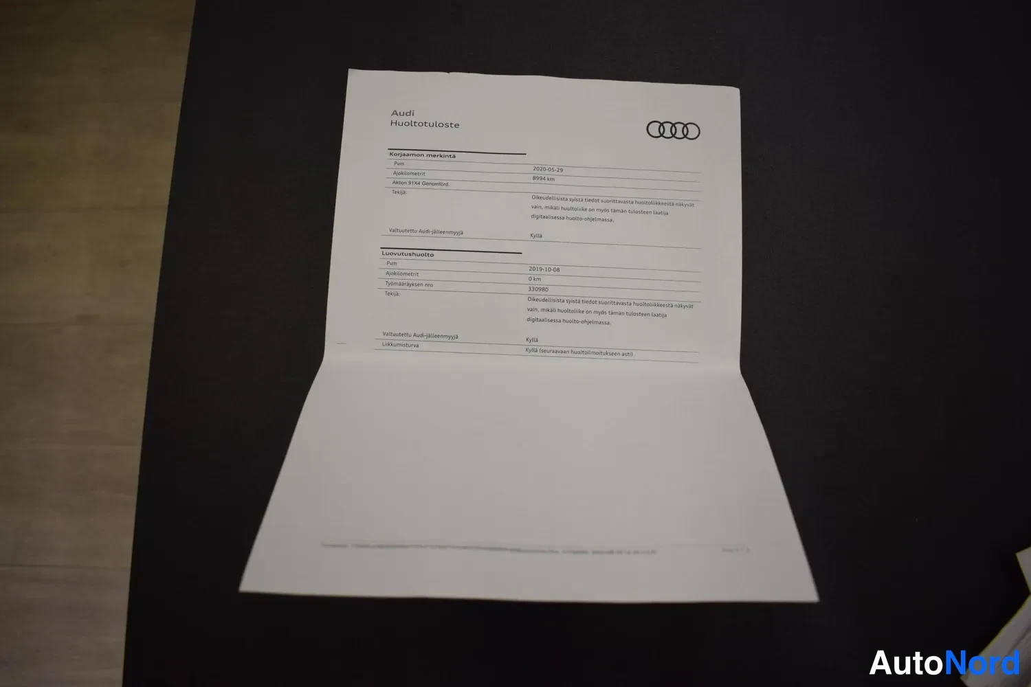 Muu: A4-paperinen huoltotodistus A3-kokoinen paperi taitettuna, Audi-logo ylhäällä, teksti 'Audi Huoltotuoste'.