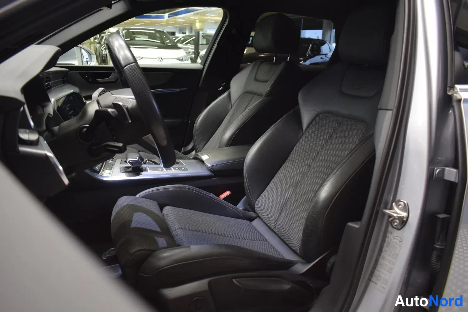 Muu: Audi A6:n etuistuimet sivulta kuvattuna kuljettajan oven auki: tummat urheiluistuimet ja osittain näkyvä ohjauspyörä.