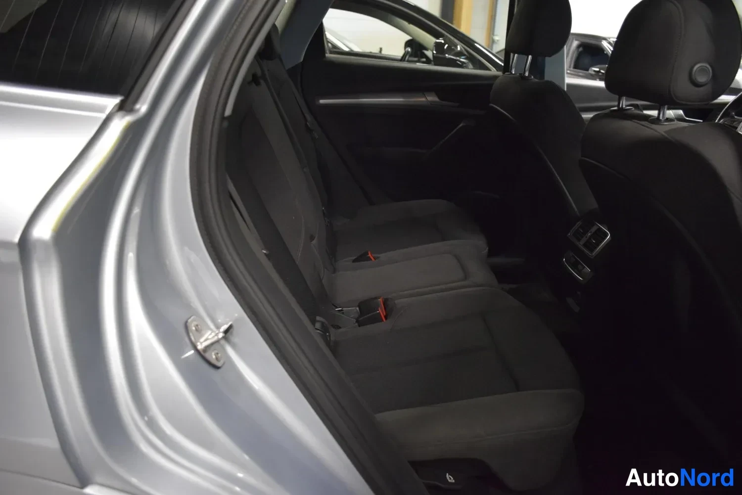 Sivulta: Audi Q5:n takaistuimet avatusta takavasemmasta ovesta katsottuna; musta kangasverhoilu ja takakonsolin ilmastointilaitteet näkyvät.