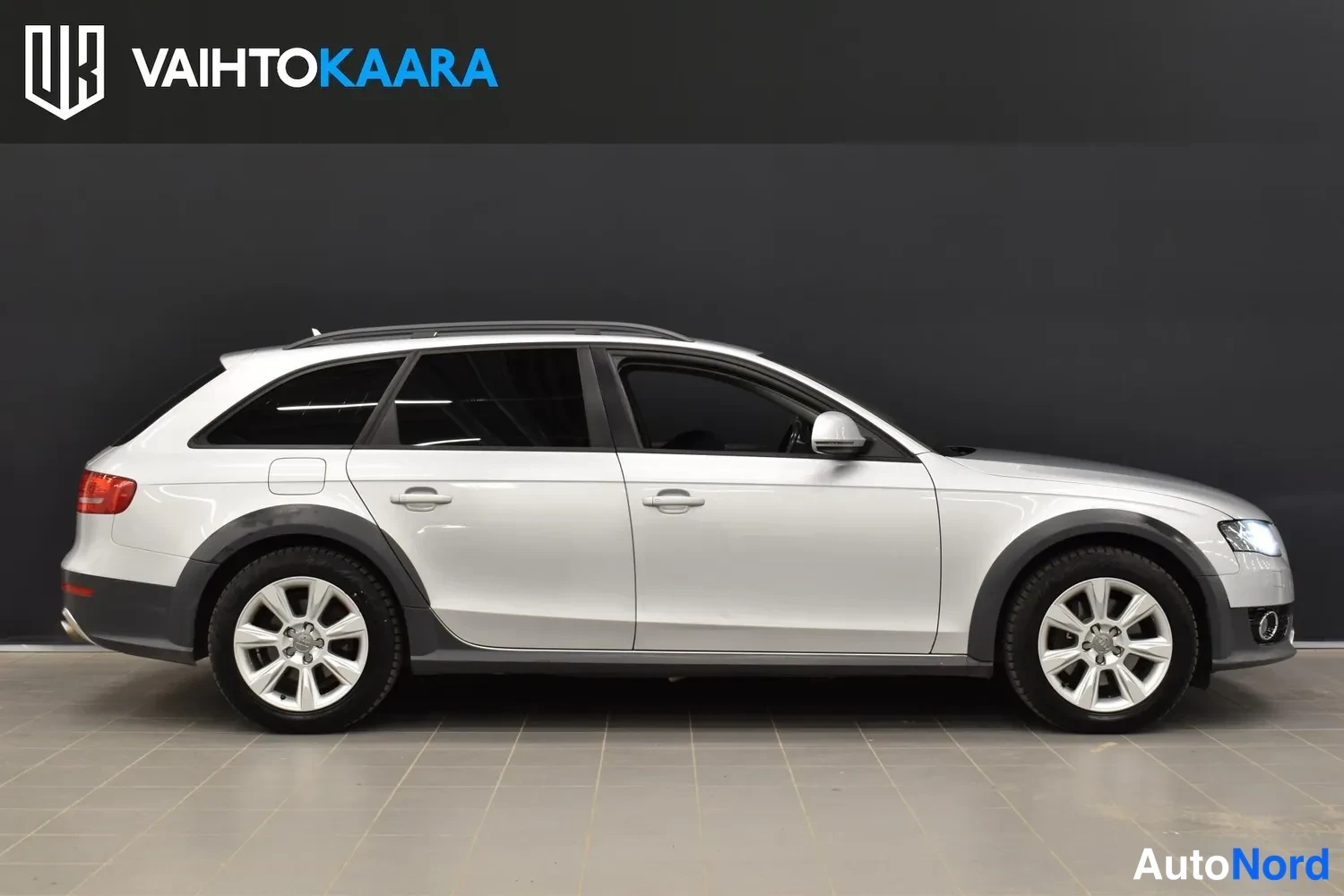 Sivulta: Audi A4 Allroad -farmariauton sivukuva oikealta puolelta, hopeinen koriväri, kattokaiteet ja tummat muovilistat