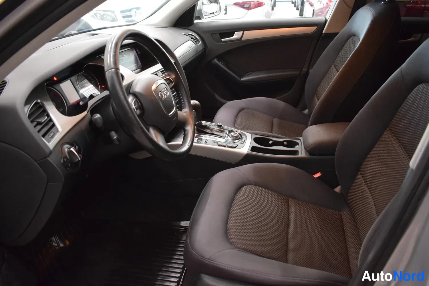 Muu: Audi A4:n etusistuin ja kojelauta sisäpuolelta, tummat kankiistuimet ja automaattivaihteen valitsin