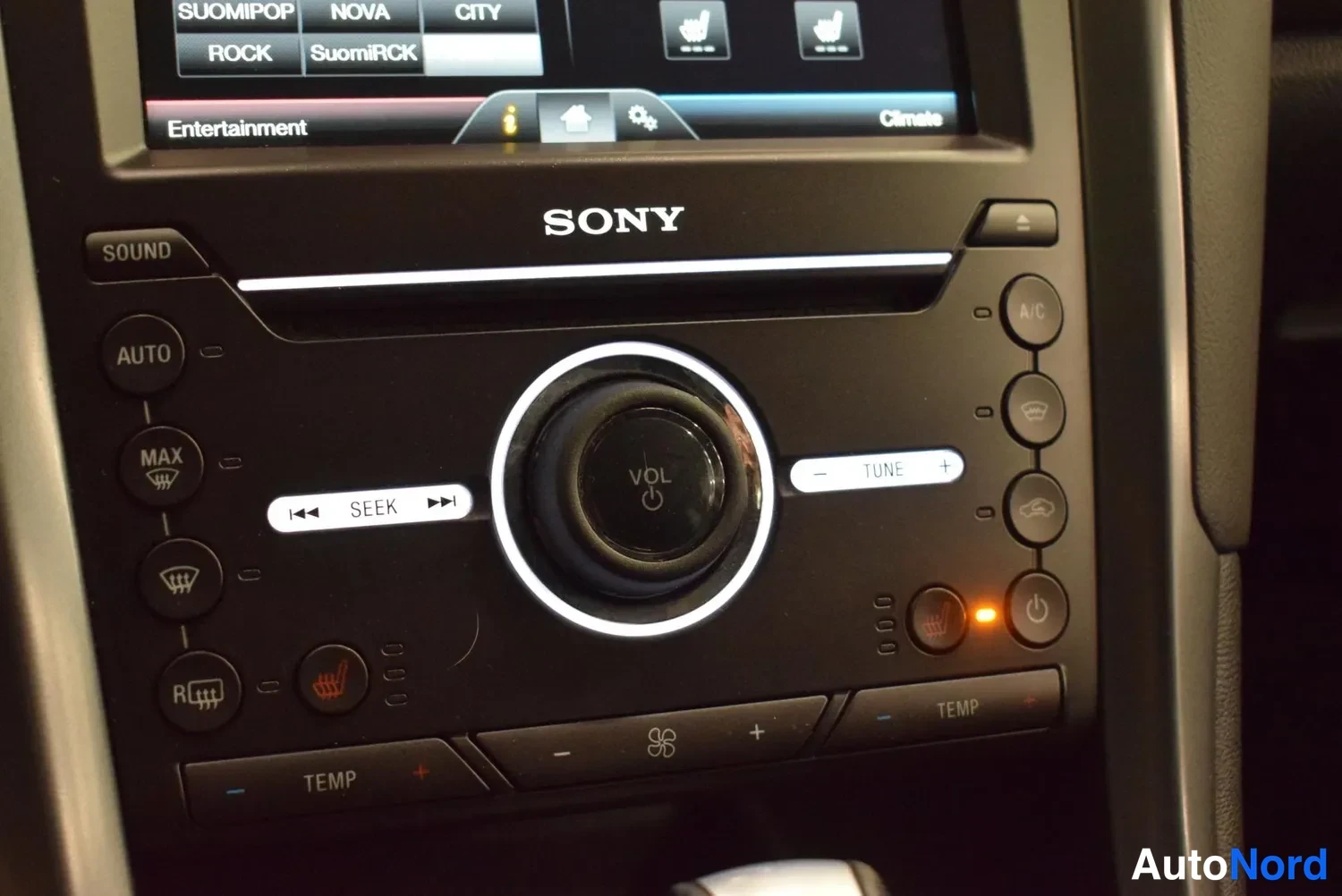 Yksityiskohta: Sony-radion ja automaattilämmityksen painikkeet: AUTO, A/C, MAX, istutinlämmityskuvakkeet, SEEK ja VOL-säädin.