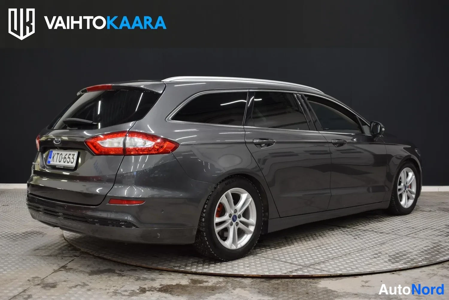 Takaviisto: Ford Mondeo -farmari takakulmasta vasemmalta, tummanharmaa metalliväri.