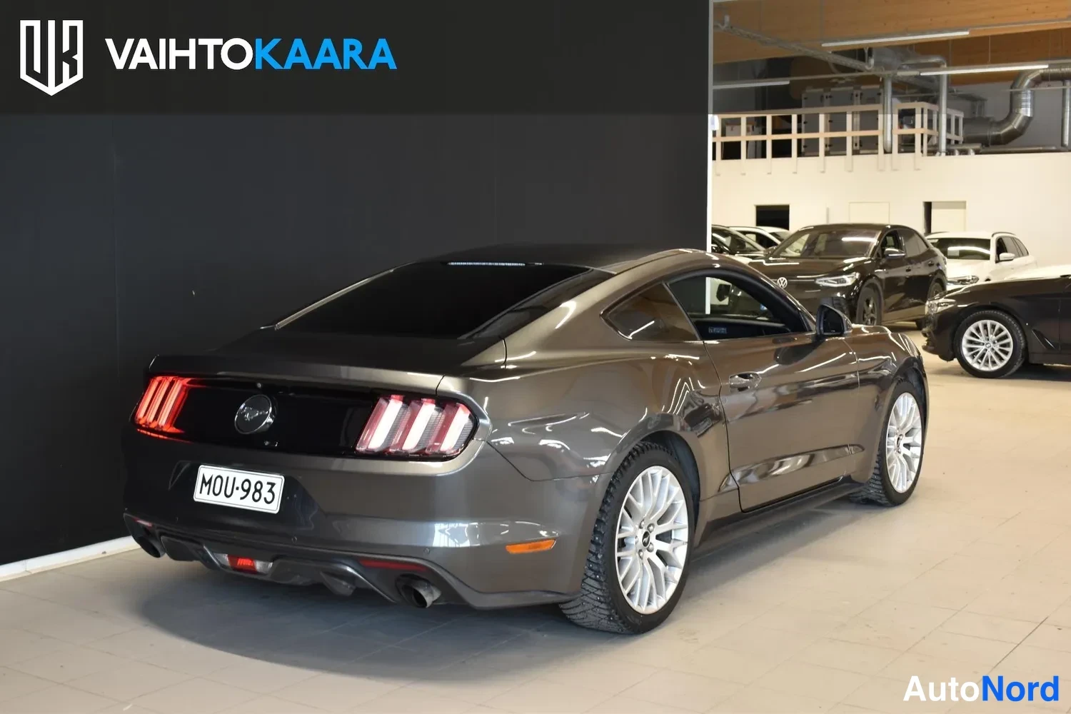 Takaviisto: Ford Mustang takaviistossa oikealta, tummanharmaa coupé rekisterillä.