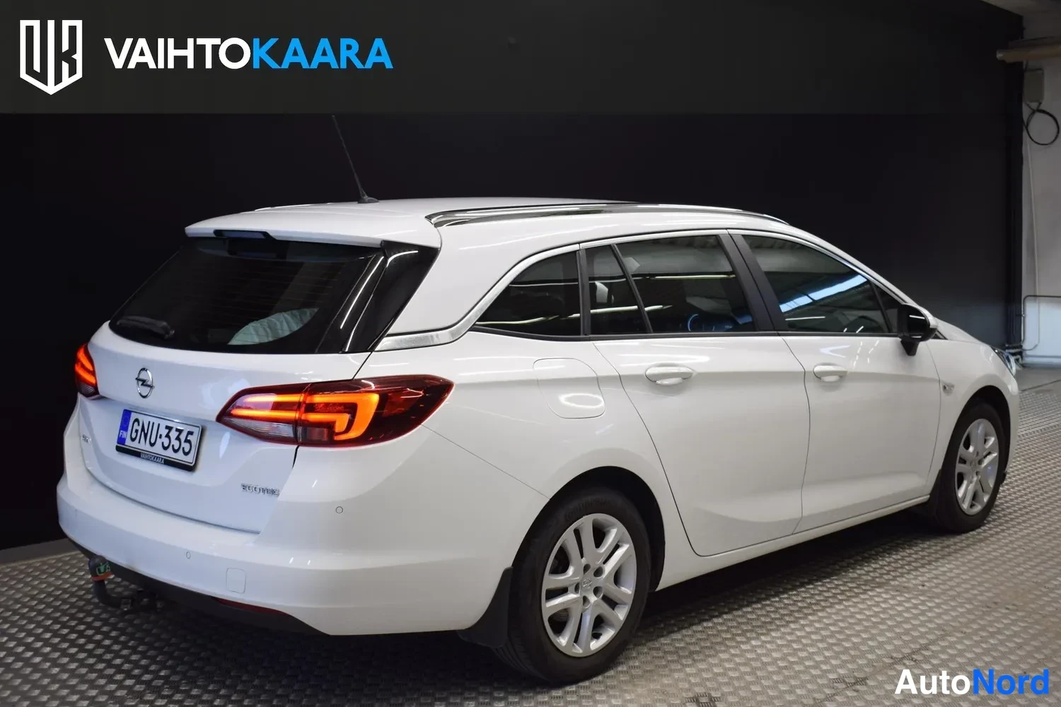 Takaviisto: Opel Astra Sports Tourer -farmari takaa vasemmalta, valkoinen kori ja tummat takavalot. Rekisteritunnus.