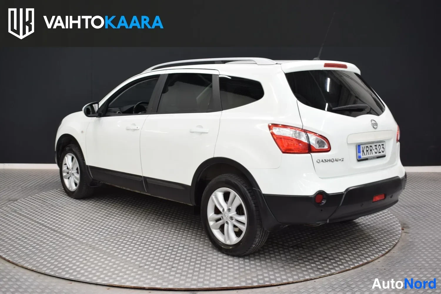 Takaviisto: Valkoisen Nissan Qashqai+2:n takakulmakuva oikealta, takapanssari ja kylki näkyvät studioissa.