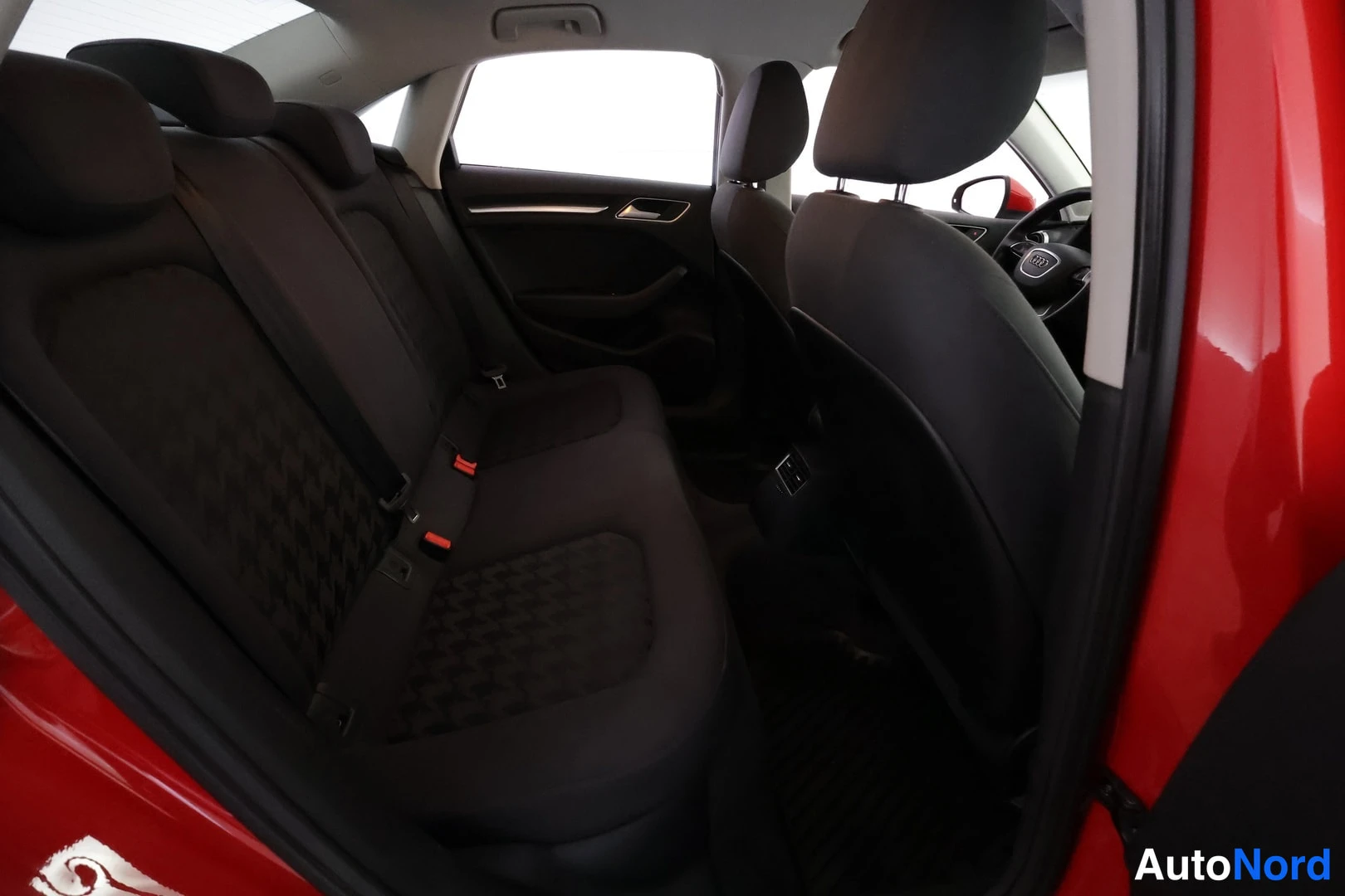 Muu: Audi-sedanin takapenkku ja etumatkustustila kankaaverhoilulla, kuvattu avatusta takaovesta.