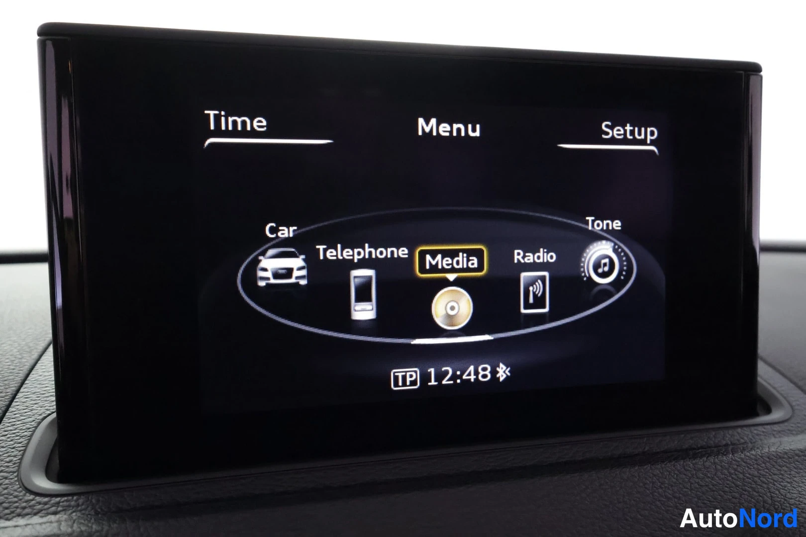 Muu: Audi A3 Sedanin kojelaudan tietoviihdenäyttö, jossa on valikko Time, Menu ja Setup; alivalikkoja Car, Telephone, Media, Radio ja Tone, kello 12:48.