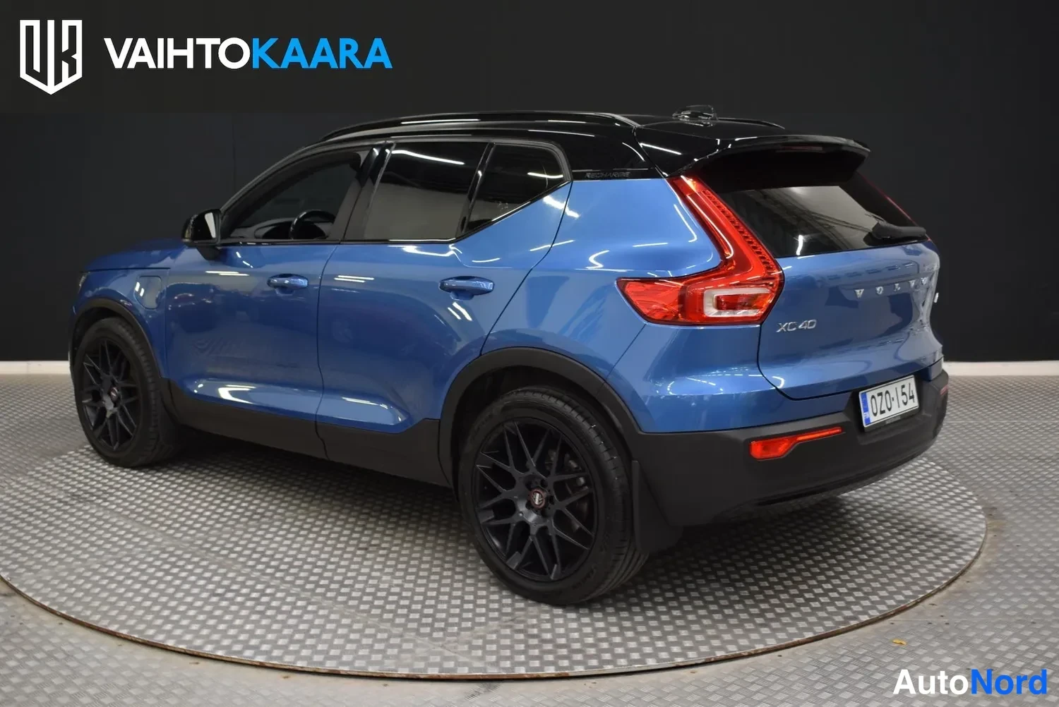Takaviisto: Sininen Volvo XC40 takaviistosta, punaiset takavalot, mustat kiiltävät vanteet, XC40-merkintä takapaneelissa, rekisteritunnus.