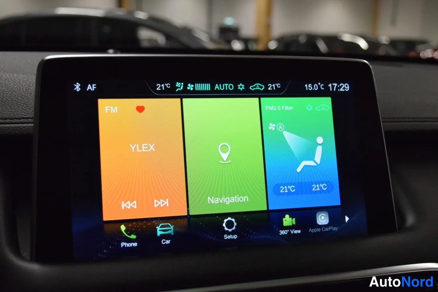 Muu: Keskikonsolin kosketusnäyttö, jossa radiovalikko YLEX, Navigation-painike ja ilmastointiasetukset 21 °C; alareunassa Phone, Car, Setup, 360 View ja Apple CarPla