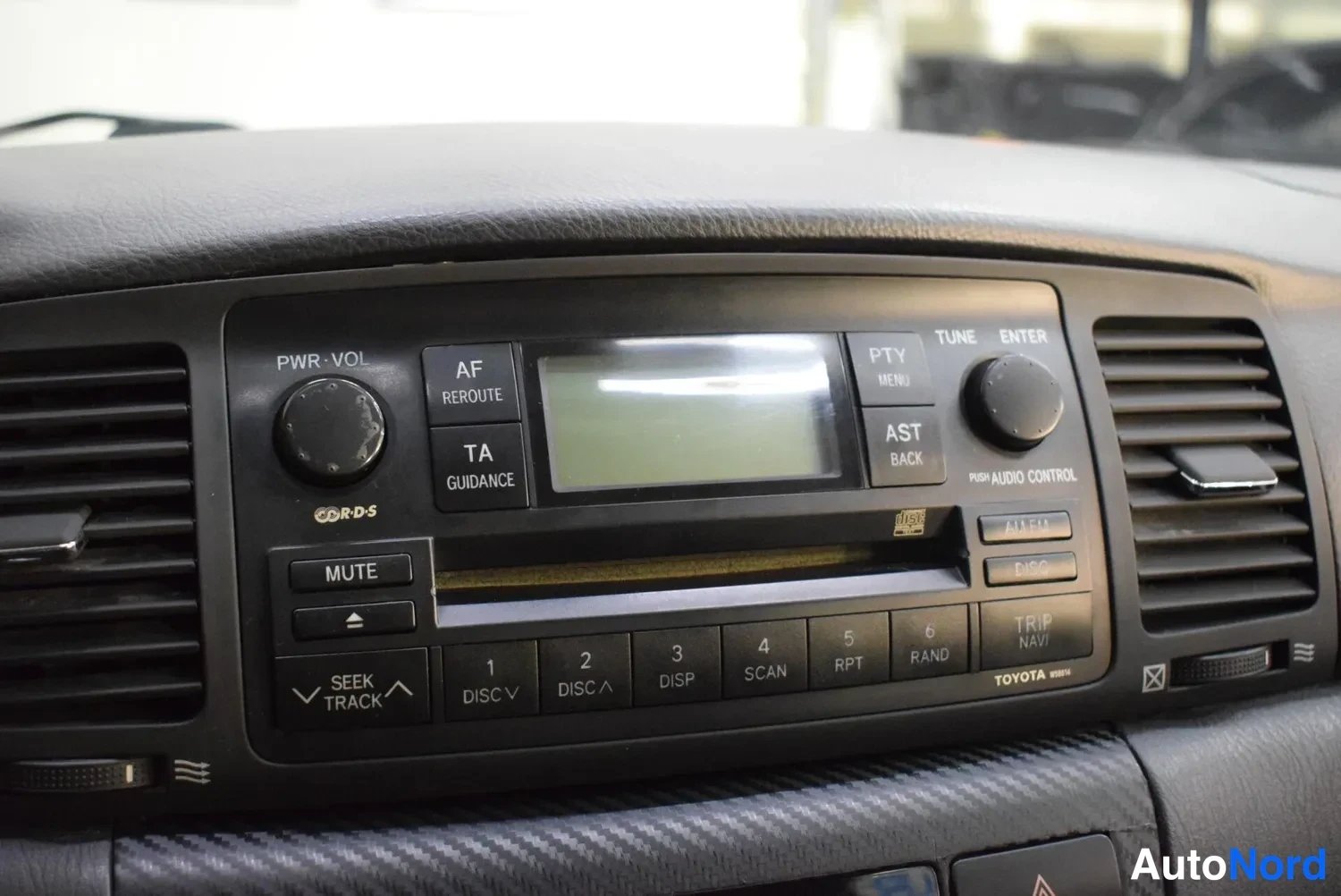 Yksityiskohta: Kojelaudan musta Toyota-radiopaneli CD-soittimella, näytöllä ja lukuisilla painikkeilla.