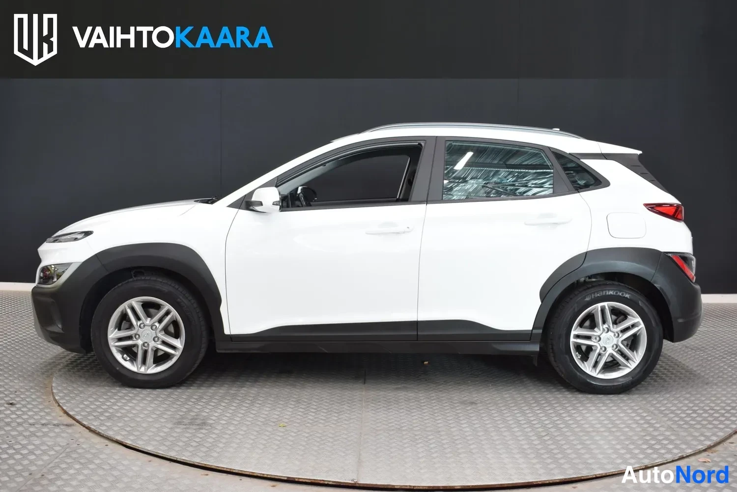Sivulta: Hyundai Kona sivulta oikealta kuvattuna, valkoinen kori, kiinteä sivupeili jaHopeavanteet.