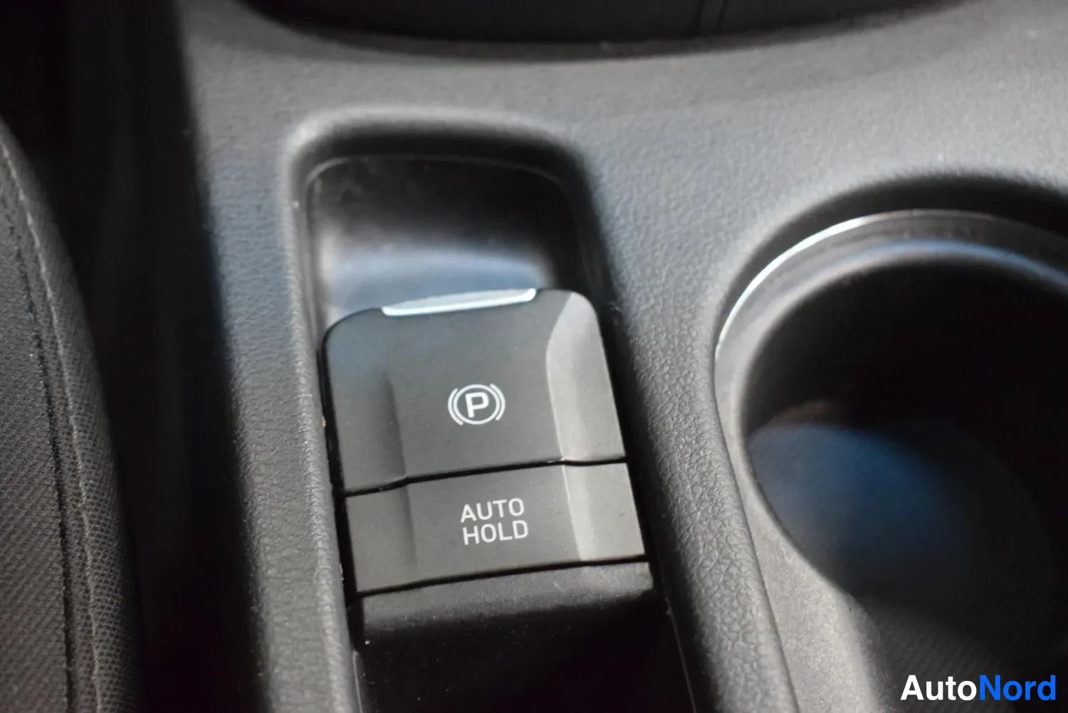 Yksityiskohta: Sähköinen käsijarrunappi (P) ja AUTO HOLD -nappi keskikonsolissa.