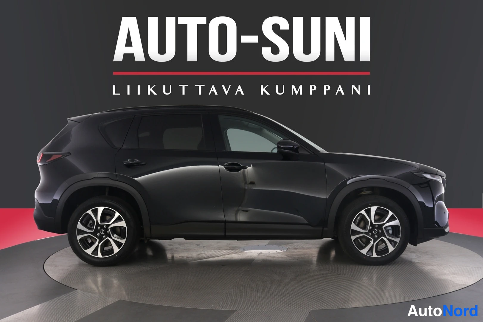 Sivulta: Musta Mazda CX-5 -henkilöauto sivuprofiilikuvassa studiotyökossa, koko kylki ja molemmat pyörät näkyvät.