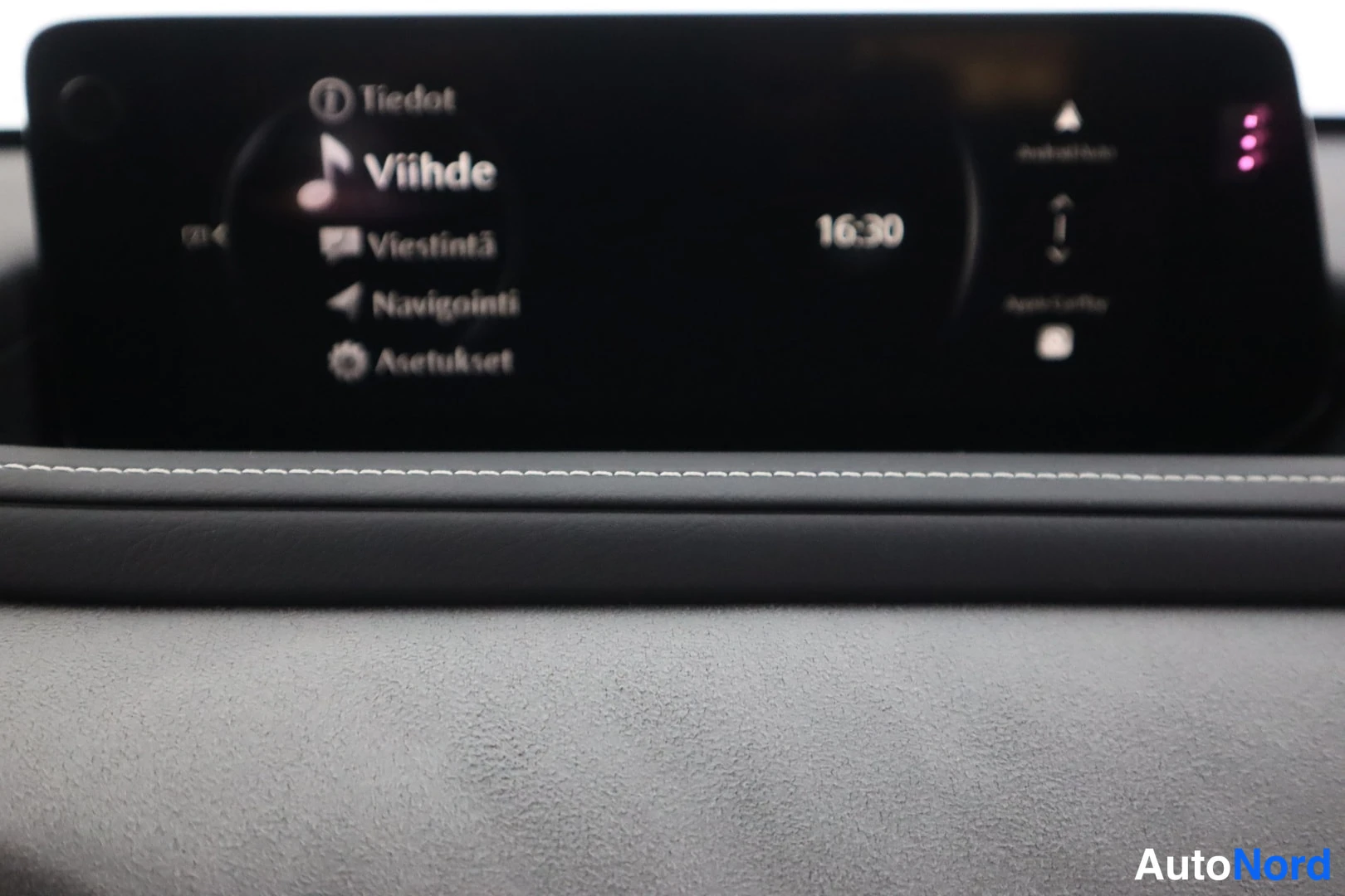 Muu: Kojelaudan näytön valikko vaihtoehdoilla Tiedot, Viihde, Viestintä, Navigointi ja Asetukset, kello 16:30; kuva on osin epätarkka.