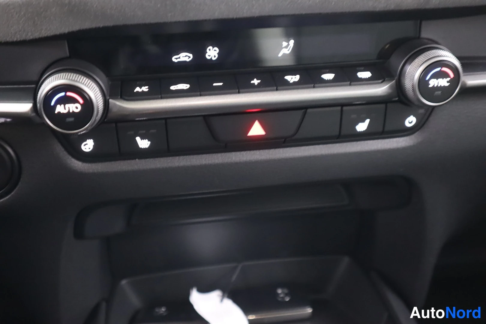Yksityiskohta: Sisätilakuva: automaatikkapaneeli näkyvissä A/C-painikkeella, AUTO- ja SYNC-säädöillä sekä VAROITUSKOLMIO-painikkeella.