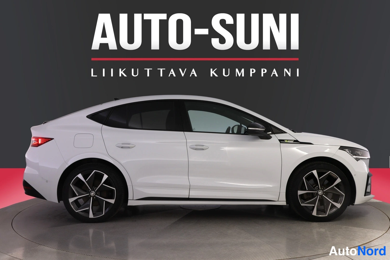 Etuviisto, nokka oikealle: Valkoinen henkilöauto kyljestä ja keulasta kuvattuna studioytymässä.