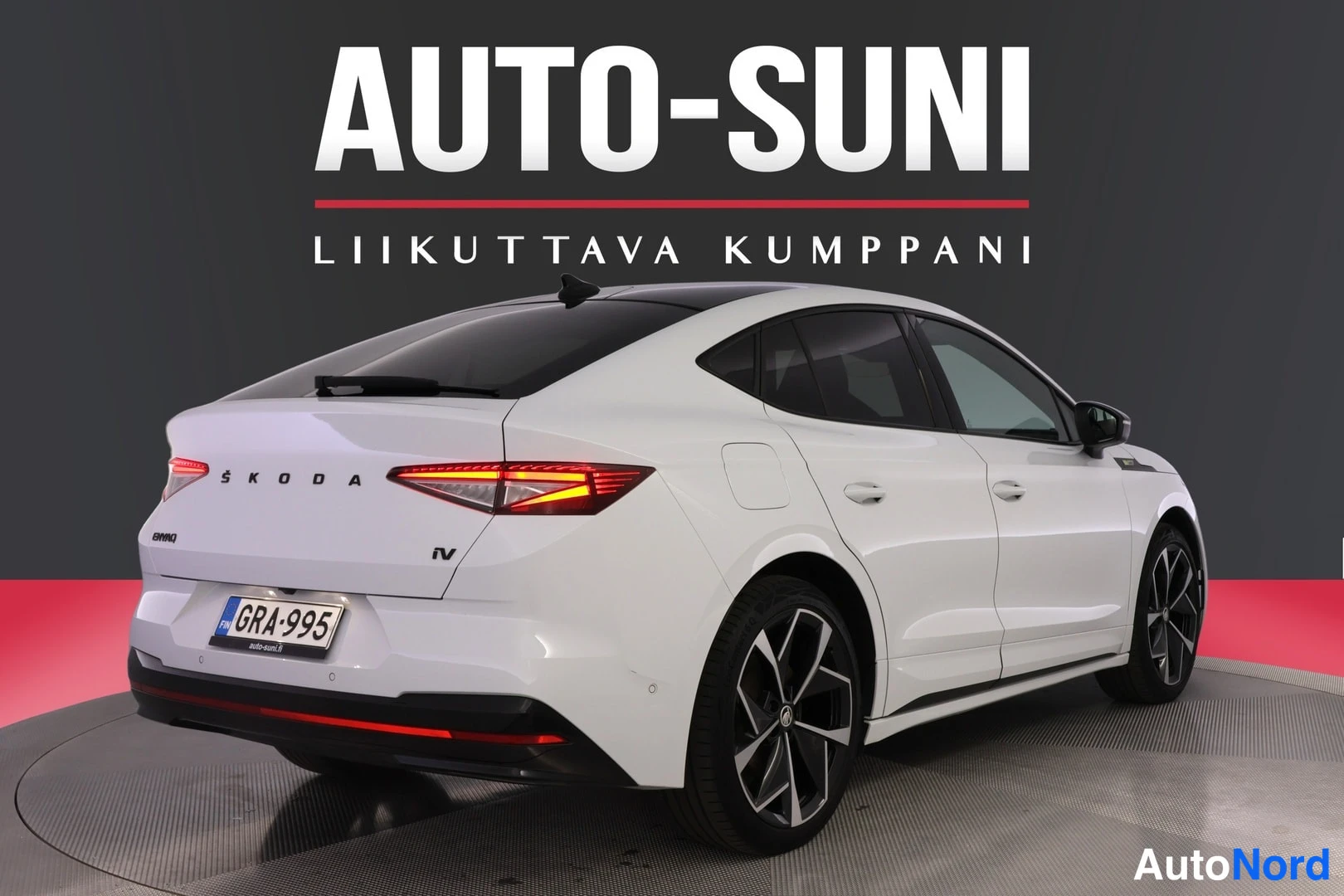 Takaviisto: Valkoinen henkilöauto kuvattuna takaa ja oikealta kyljestä; rekisterikilpi, musta katto ja tummat kevytmetallivanteet.